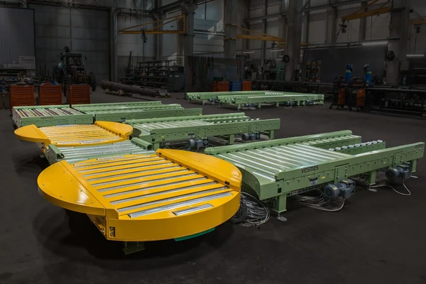 Vesmes roller conveyor system with turntables in a production hall – industrial material handling.